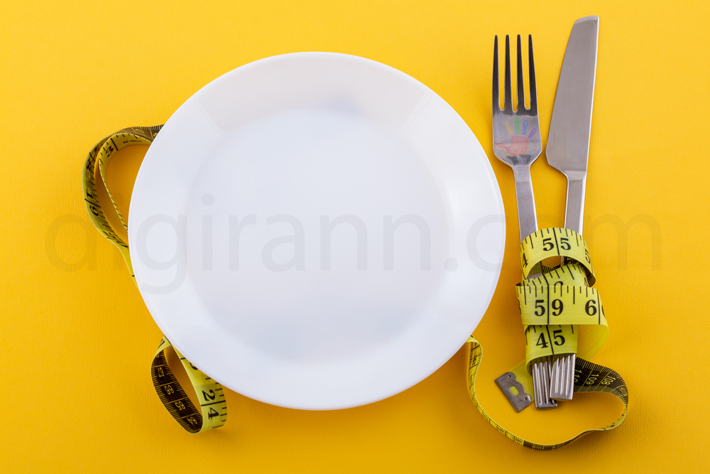 کارد و چنگال بشقاب سفید با نوار اندازه گیری زرد مفهوم رژیم غذایی کاهش وزن