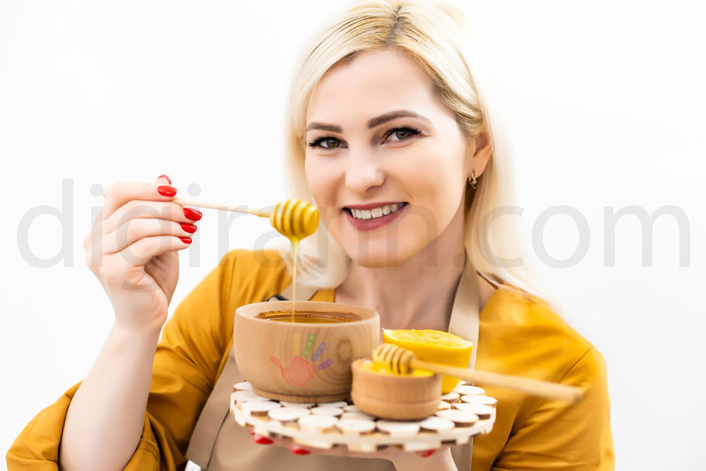 نمایی از بهترین زمان خوردن عسل یک زن جوان با موهای بلوند و لباس زرد خردلی