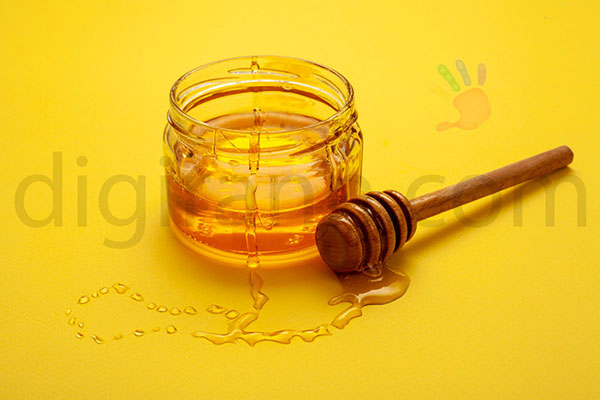 نمایی از تاریخ انقضا عسل شیشه کوچک نیم کیلویی با قاشق چوبی عسلخوری