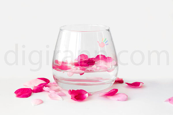 تصویری از تنگ شیشه ای محتوی گلبرگ هایی از گل محمدی سفید صورتی و قرمز برای ذکر خواص گلاب برای بدن