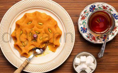 عصرانه سنتی ایرانی حلوا با گلاب در کنار چای قند پهلو روی میز چوبی