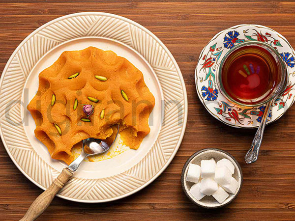 عصرانه سنتی ایرانی حلوا با گلاب در کنار چای قند پهلو روی میز چوبی